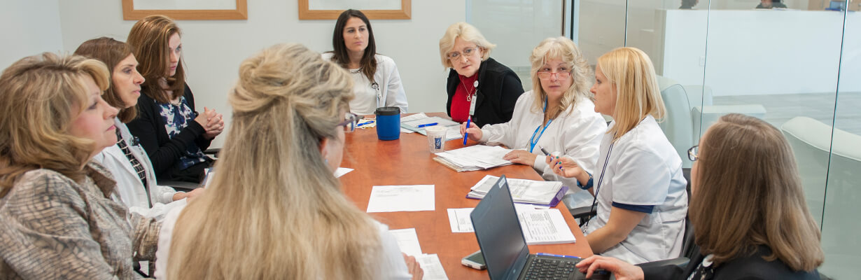 A group of female staff members sitting around a table in a conference room.
