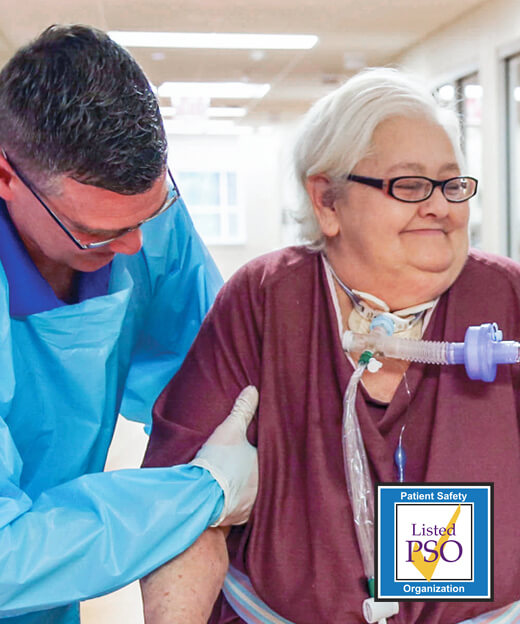 An elderly patient smiling as she learns how to walk again with her male physical therapist.